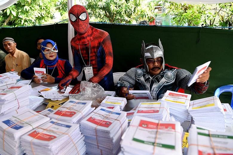 Election officials dressed in costume to match the horror theme at a polling station in Lebak Bulus, Jakarta. Officials wearing superhero costumes preparing ballot papers in Surabaya, East Java. Efforts to increase voter turnout have taken on added u