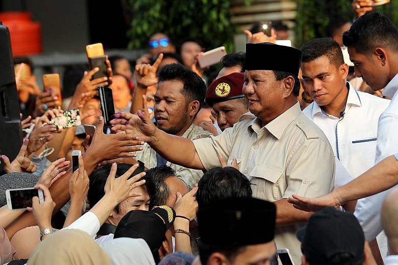 Presidential candidate Prabowo Subianto (third from right) with supporters yesterday in Jakarta. He cast doubt on the impartiality of pollsters tasked with tallying unofficial preliminary results, and called on his supporters to keep calm and "overse