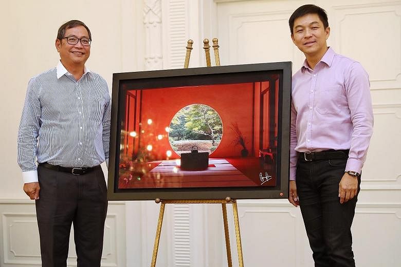 Speaker of Parliament Tan Chuan-Jin (at left) presenting a metallic print of his photograph to Maybank Singapore deputy CEO Allen Ang during a tea reception for the contributors. Maybank Singapore picked The Straits Times School Pocket Money Fund as 