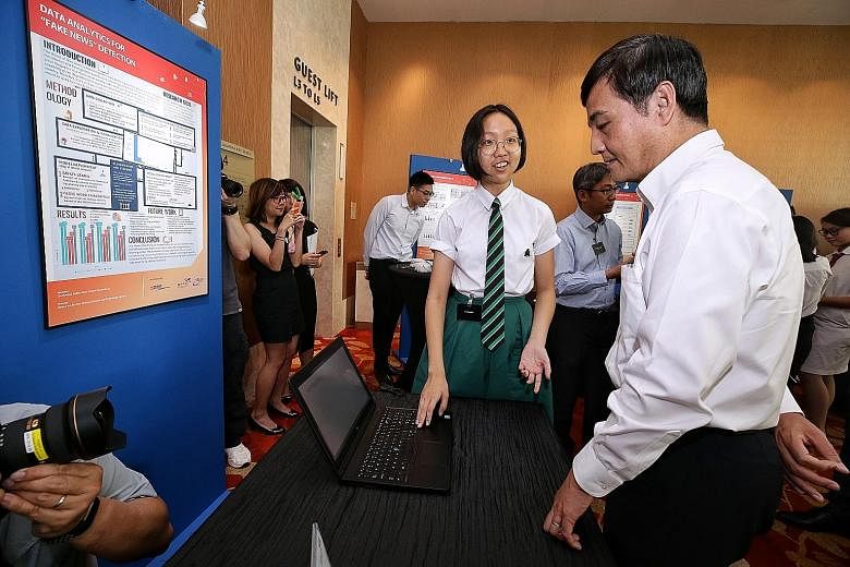 Raffles Institution student Liu Haohui explaining her project to detect fake news to Senior Minister of State for Defence Heng Chee How at the Young Defence Scientists Programme exhibition yesterday.