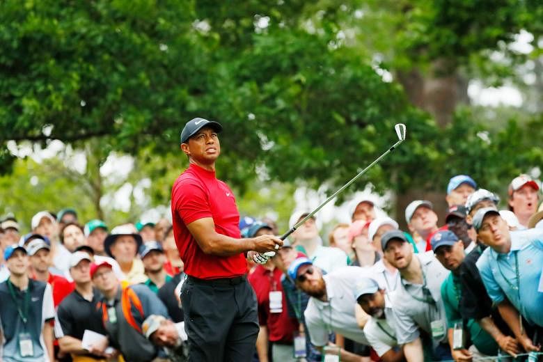 Tiger Woods watching his tee shot on the fourth hole in the final round of the Masters last Sunday. Huge crowds followed him on all four days at Augusta and roared when he won his fifth Masters and 15th golf Major. PHOTO: AGENCE FRANCE-PRESSE