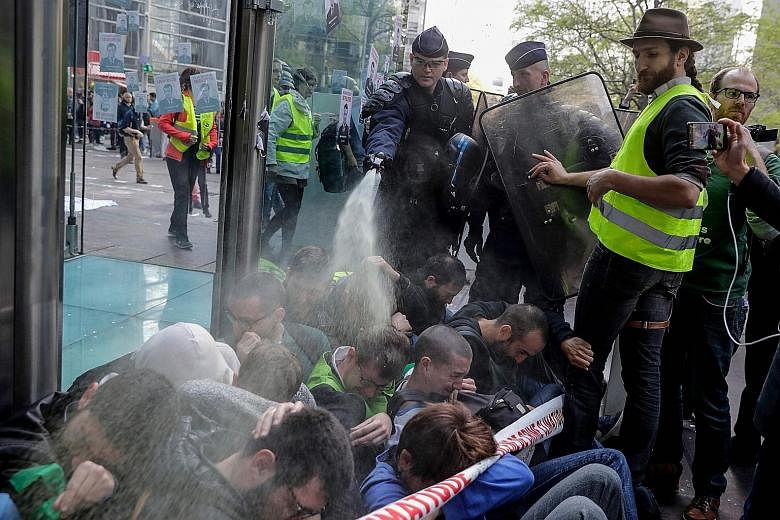 A French anti-riot police officer using pepper spray on climate-change activists as they blocked the entrance of the Societe Generale bank headquarters in a sit-down protest in Paris yesterday. PHOTO: AGENCE FRANCE-PRESSE