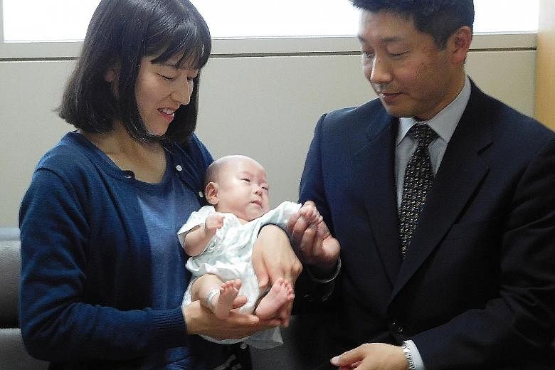 Tiny Ryusuke Sekiya in Nagano Children's Hospital in central Japan in a photo (above) taken on Oct 5 last year, just days after his birth, and pictured with his parents yesterday (right), ahead of the six-month-old's discharge this weekend. He weighe