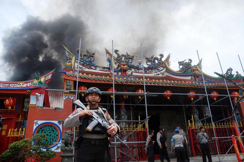 Indonesian policemen standing guard as firefighters worked to control a blaze at the Samudra Bhakti temple in Bandung on the first day of Chinese New Year on Feb 5. The fire was allegedly caused by lit prayer candles inside the temple that had been b