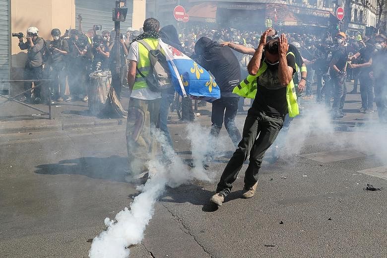 Protesters running away from a cloud of tear gas at a demonstration during the 23rd consecutive Saturday of protests by the Yellow Vest movement in Paris yesterday. PHOTO: REUTERS