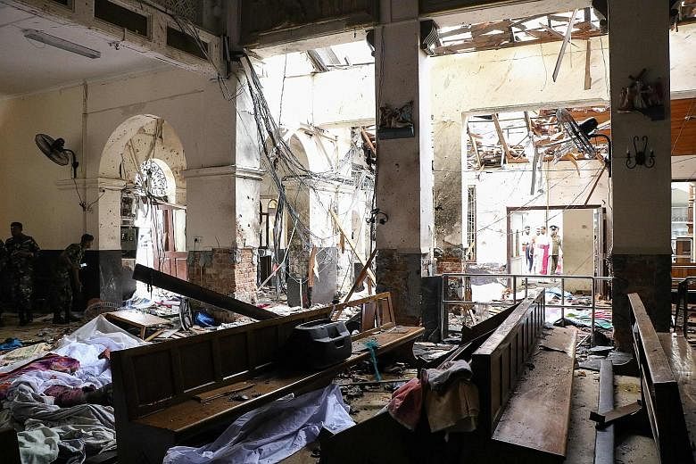 Sri Lankan security personnel at the scene following an explosion at St Anthony's Shrine in Kochchikade in Colombo yesterday, as victims' bodies lay covered with blankets amid the debris.