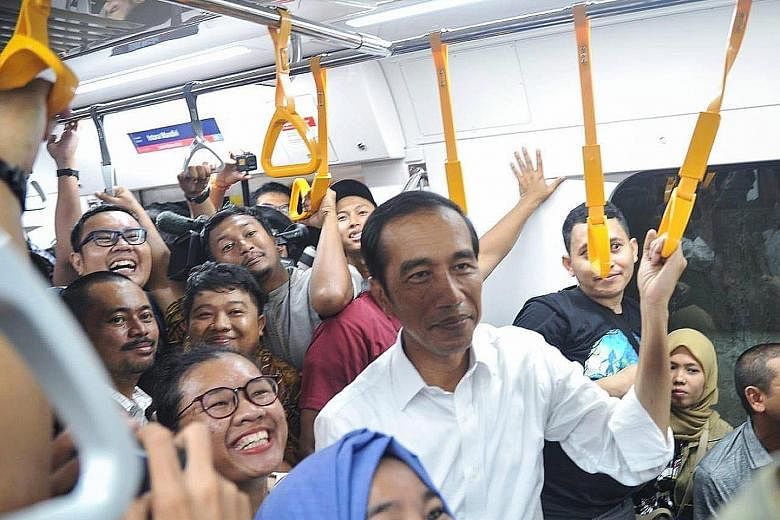 President Joko Widodo surrounded by commuters while taking the new MRT line in Jakarta on Sunday. Quick-count results by local pollsters showed the President as most likely to win the election, a result now being contested by his opponent, Mr Prabowo