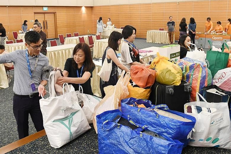 The Straits Times travel writer Lee Siew Hua (second from left) donating a large bag of clothes during the textile donation drive at SPH's Earth Day 2019 yesterday - an annual environmental awareness event organised by Singapore Press Holdings. About