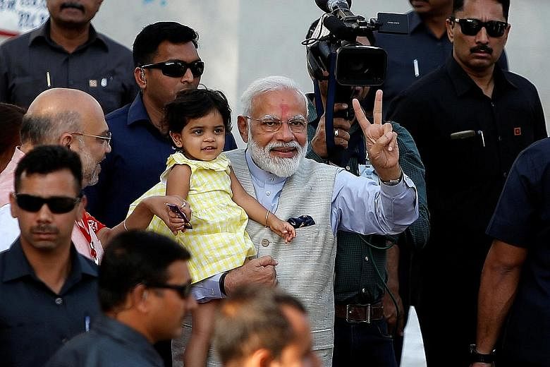 India's Prime Minister Narendra Modi holding the granddaughter of India's ruling Bharatiya Janata Party president Amit Shah after he arrived to cast his vote at a polling station yesterday during the third phase of general elections in Ahmedabad in t