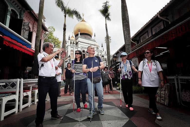 Senior ambassador Chhua Bak Siang (far left) guiding visually impaired participants from Guide Dogs Singapore, including masseur Tan Chiew Song (in blue), around Kampong Glam heritage precinct, as part of the NHB's Reminiscence Walks programme.