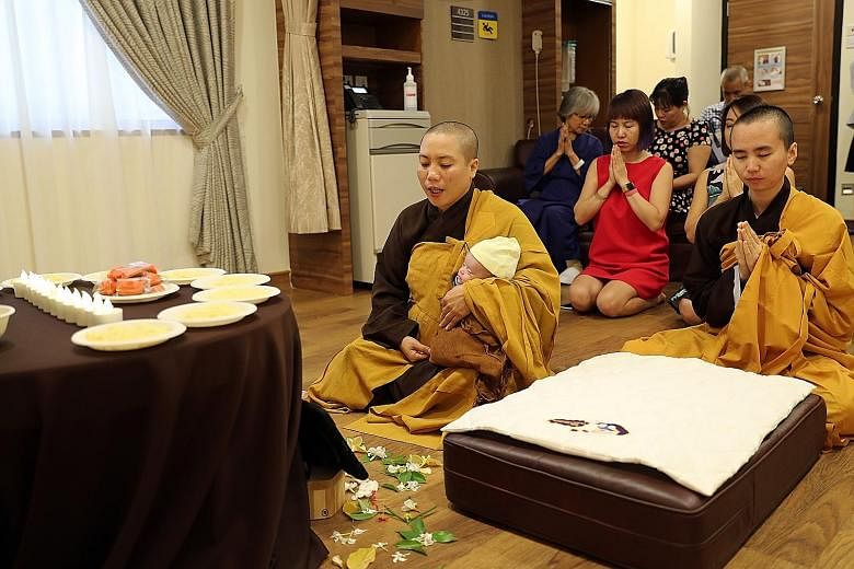 Venerable Minh Tai, with baby Trieu Hoai An in her arms, and her disciple Thien Ngo praying for blessings and fortune for the baby as they marked her "day thang", or full month in Vietnamese, yesterday. Also celebrating with them were hospital staff 