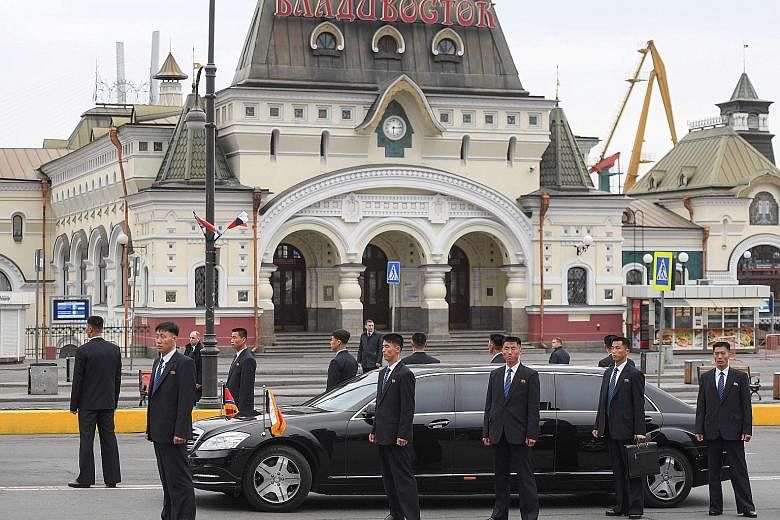 Above: North Korean leader Kim Jong Un attending a welcome ceremony after arriving at Vladivostok railway station in his private train yesterday. Right: Bodyguards around a limousine that was part of Mr Kim's motorcade outside Vladivostok railway sta