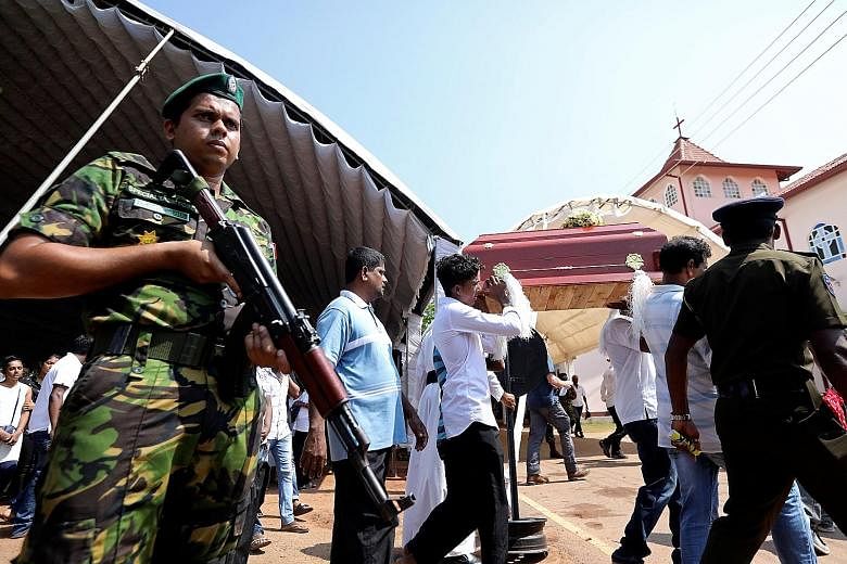 A soldier on the alert at yesterday's funeral in Negombo of an eight-month-old victim of the Easter Sunday blasts.