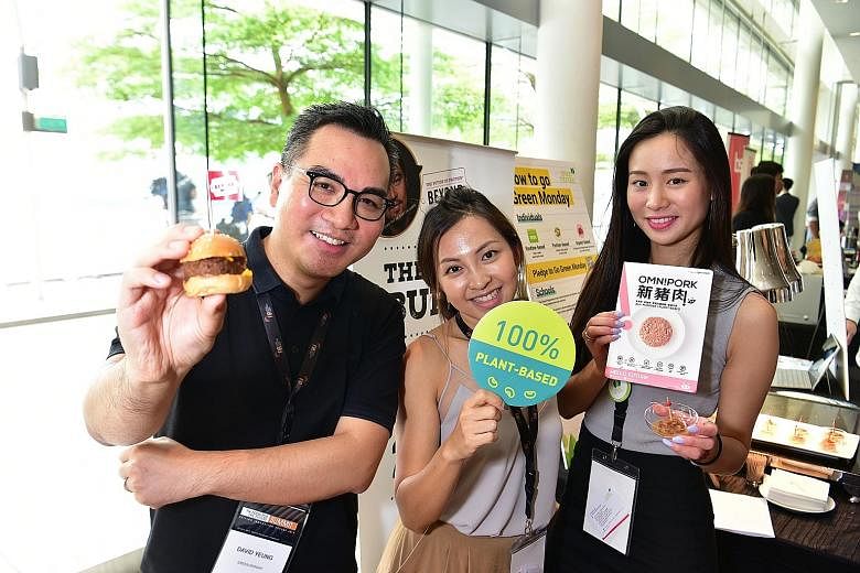 Mr David Yeung, founder and chief executive of social venture group Green Monday, holding a burger made from 100 per cent plant-based meat products at the Food Industry Asia Food for the Future Summit at Marina Bay Sands yesterday. With him are his s