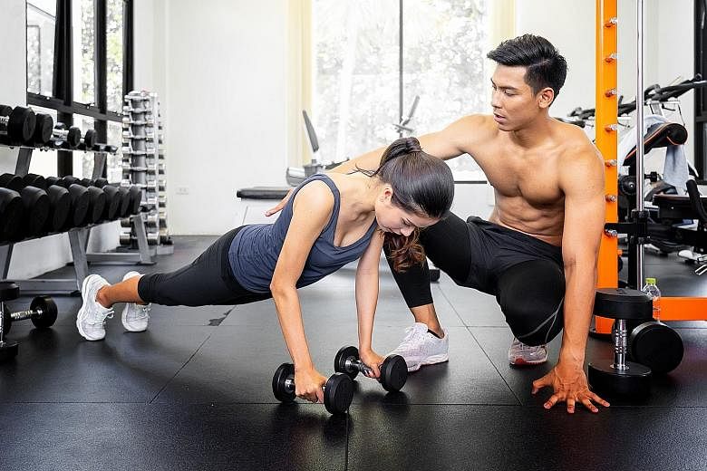 A personal trainer showing his trainee the high plank start position for bicep curls. PHOTO: ISTOCKPHOTO
