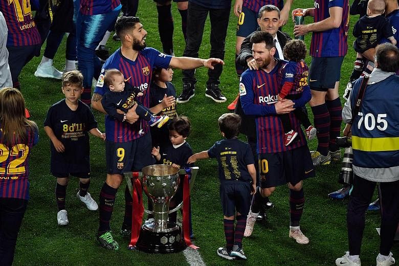 Barcelona's Luis Suarez and Lionel Messi, with their children, celebrating with the LaLiga trophy after beating Levante 1-0 at the Nou Camp on Saturday. It is Messi's eighth league title in 11 years, and the club's 26th overall.