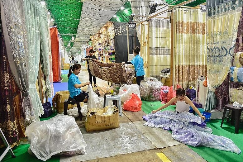 Workers from H. M. Curtain setting up their store yesterday at the Hari Raya Bazaar, which opens on Friday. The launch of the light-up will also see entertainers performing a medley of 1960s Malay songs.