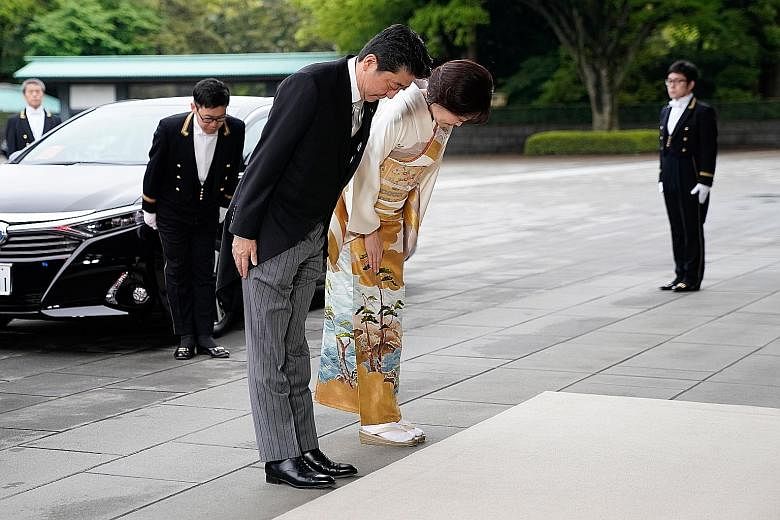 Prime Minister Shinzo Abe (above) and his wife Akie Abe bowing as they arrived for Emperor Akihito's abdication ceremony at the Imperial Palace in Tokyo yesterday. PHOTO: BLOOMBERG Left: Emperor Akihito (far left) attending the Taiirei Tojitsu Kashik