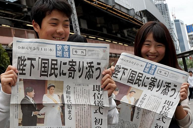 People in Tokyo yesterday showing a newspaper's extra edition reporting Emperor Naruhito's accession to the throne.
