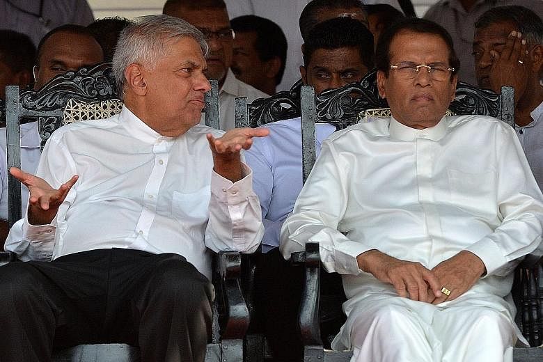 Sri Lanka's Prime Minister Ranil Wickremesinghe (left) and President Maithripala Sirisena at a public event yesterday. Many Sri Lankans believe a rift between both leaders has undermined national security. A Sri Lankan Muslim woman and a man being ch