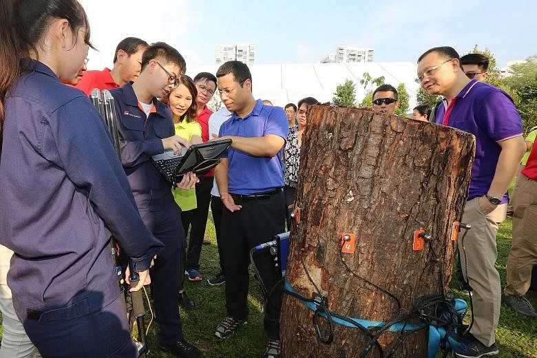 Second Minister for National Development Desmond Lee (centre) being briefed by students on how they use equipment to assess the condition of trees. He said that adopting more advanced technology will not only improve productivity but also attract a n