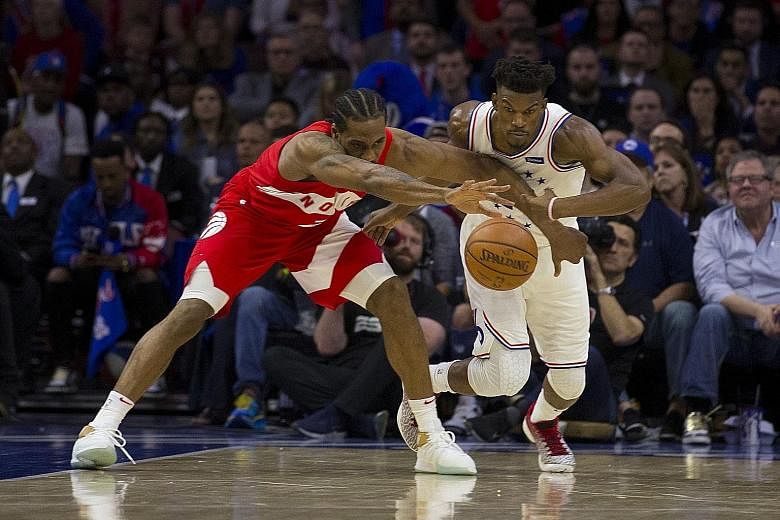 The Raptors' Kawhi Leonard and the 76ers' Jimmy Butler fighting for the ball in Toronto's 101-96 win in Philadelphia on Sunday. PHOTO: AGENCE FRANCE-PRESSE
