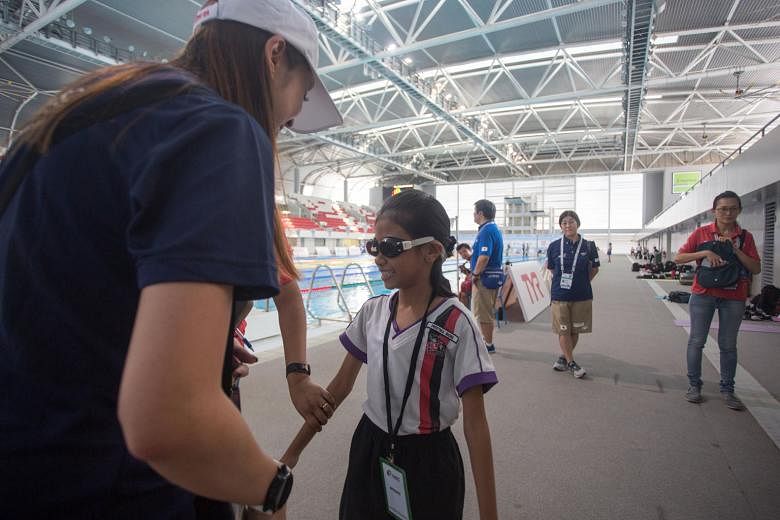 Radin Mas Primary School pupil Preetika Riona trying out blackened goggles for visually impaired students on Tuesday at the OCBC Aquatic Centre. She is one of over 50 students from Radin Mas and Bukit Panjang Government High who attended a learning j
