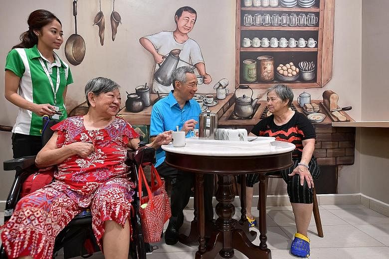 Prime Minister Lee Hsien Loong chatting with nursing home residents Chew Eng Huay (seated far left), 73, and Hea Eng, 59, at the official opening of Ren Ci @ Ang Mo Kio Nursing Home yesterday.