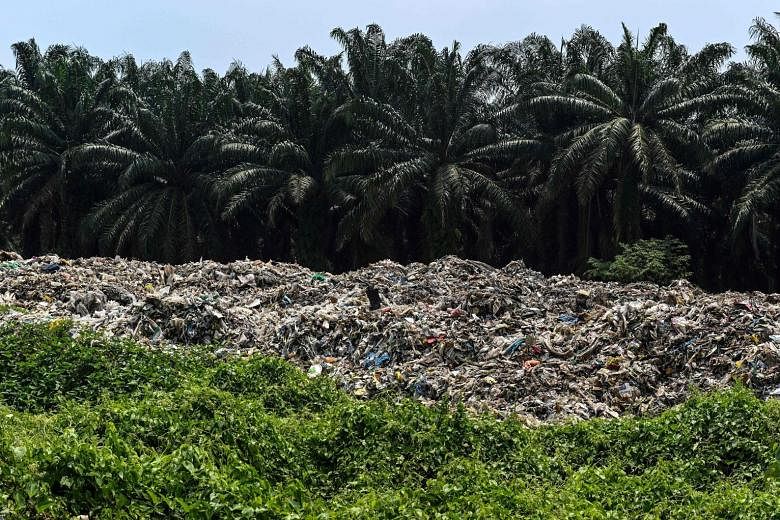 Plastic waste near palm oil trees at an abandoned factory in Jenjarom, a district of Kuala Langat, outside Kuala Lumpur. In Malaysia, huge amounts of imported plastic waste have ended up being dumped in the countryside.