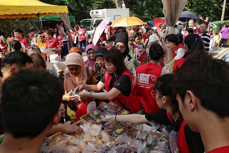 Residents queueing up for fresh produce at a Food From The Heart booth during yesterday's carnival to celebrate Marine Parade Town Council's 30th anniversary. 