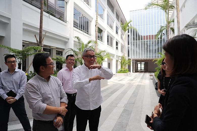 Far left: (From left) Mr Ho Weng Hin, Mr Han Kok Juan and Mr Mok Wei Wei in one of the building's courtyards. Refurbishment work included reinstating the neutral tones of the building facade (above) and constructing an overhead link bridge (left).