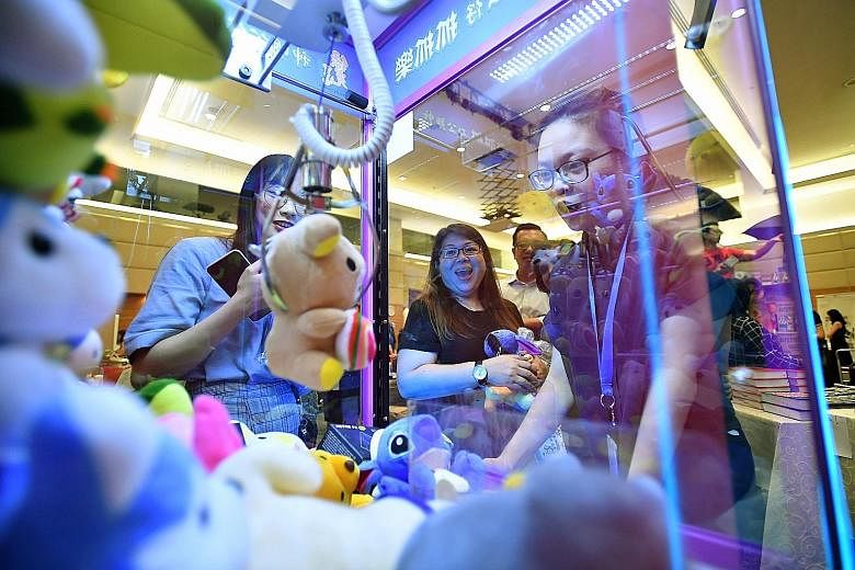 SPH customer service officer Wong Su Yi, 19, trying her luck at an arcade claw machine. It was one of the attractions at yesterday's SPH Charity Carnival, which boasted 35 stalls and raised more than $31,000.