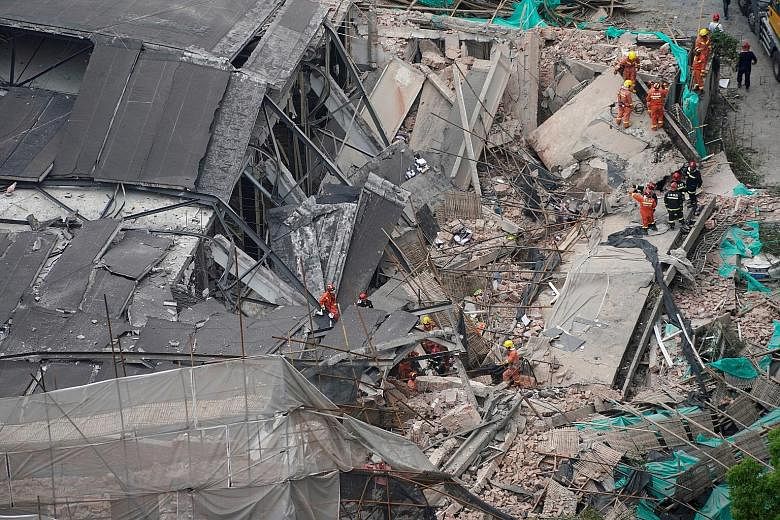 Firefighters looking for survivors at the site of the collapsed commercial building in central Shanghai, China, yesterday.