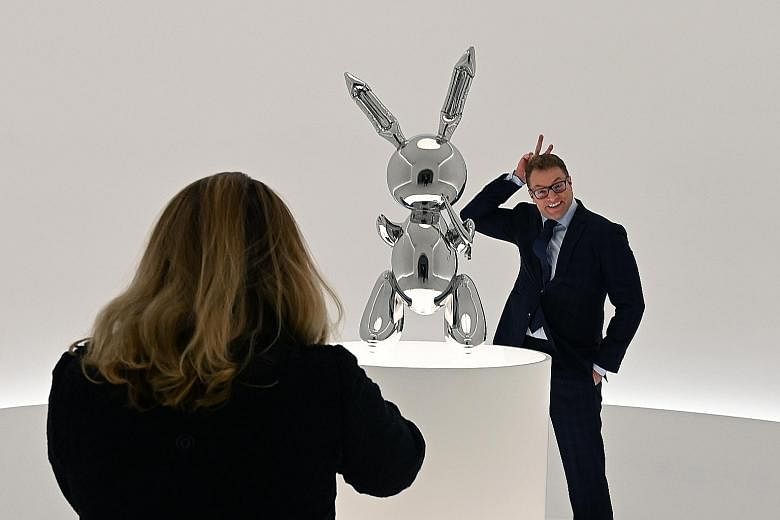 A visitor (above) striking a pose next to artist Jeff Koons' (left) Rabbit sculpture at a preview for Masterpieces from The Collection of S.I. Newhouse at Christie's New York earlier this month.