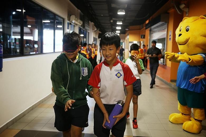 Above: Mr Lawrence Tan, 66, who is partially blind, spoke about his personal experiences on public transport at yesterday's exhibition launch. Left: Sengkang Primary School pupil Hedrian Al-Shahiryn Hairul Nizam, 12, wears a blindfold to simulate the