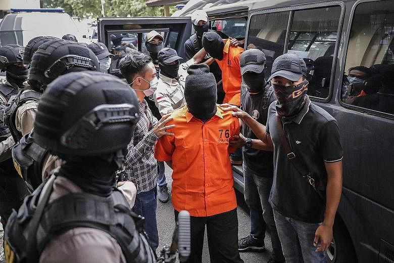 Suspects being escorted by anti-terror police officers before a press conference at the police headquarters in Jakarta yesterday. Six of the nine men nabbed had travelled to join ISIS in Syria.