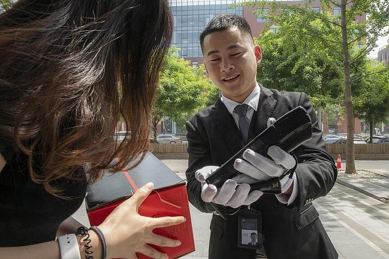 A driver for JD.com's Luxury Express delivery service getting a customer in Beijing to acknowledge receipt on a handheld device. Big names in luxury are teaming up with Internet companies to offer sales and services, like JD.com's white-gloved butler