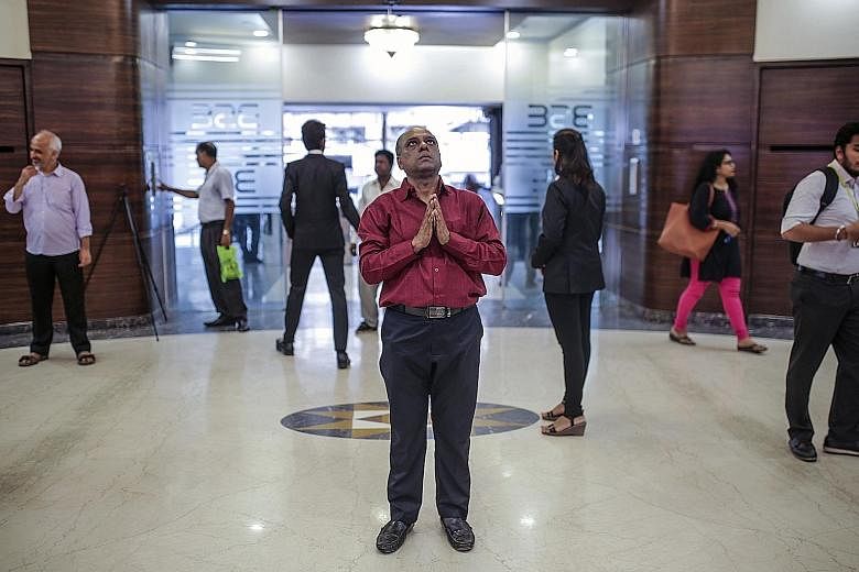 A man praying to a deity on display at the Bombay Stock Exchange building in Mumbai. The exchange's Sensex index had its biggest one-day gain in nearly six years to close at a record high, while the rupee strengthened against the US dollar.