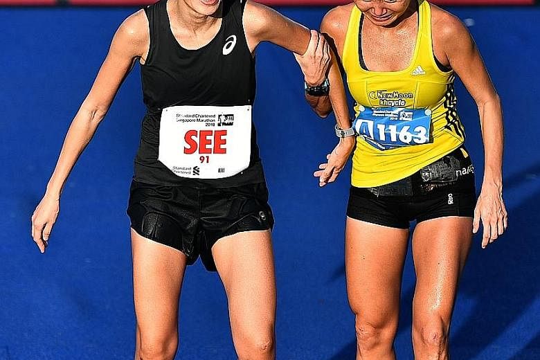 Lim Baoying helping Rachel See after the latter crossed the finish line at the Standard Chartered Singapore Marathon on Dec 9 last year. The change in standings means See retained her 2017 title.
