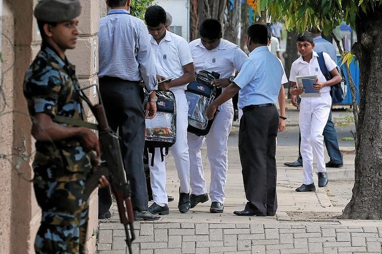 A Sri Lankan soldier on guard at the entrance to St Joseph's school as staff search students' bags. Catholic schools reopened yesterday, a month after the deadly Easter Sunday bombings in Colombo.
