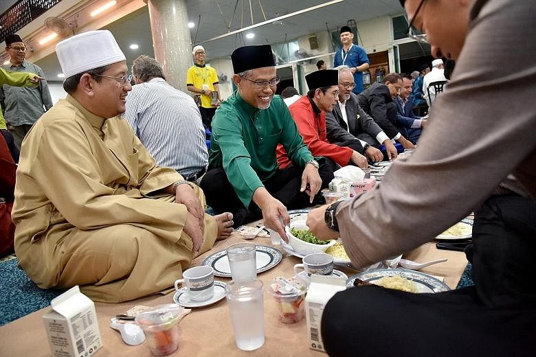 Members and leaders of the Muslim community with Minister in-charge of Muslim Affairs Masagos Zulkifli (in green shirt) having a meal of mandi rice after breaking fast yesterday at the Masjid Al-Istiqamah in Serangoon. Mr Masagos, who is also the Min