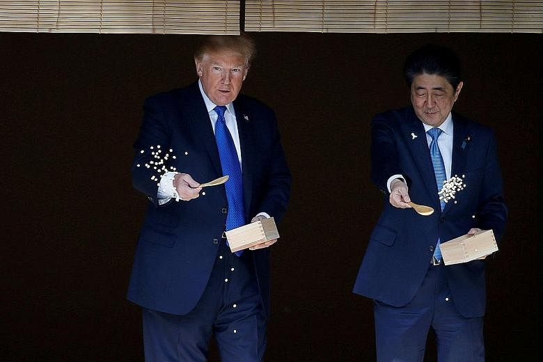 US President Donald Trump and Japanese Prime Minister Shinzo Abe feeding carp before their working lunch at Akasaka Palace in Tokyo last November. The Japanese government is taking unprecedented steps to wow Mr Trump upon his arrival in Tokyo on Satu