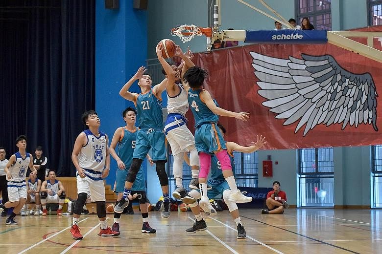 Tampines Meridian Junior College captain Tiong Chuan Yao attacking the rim despite being guarded closely by Anderson Serangoon Junior College's Louis Ho (right) and Keith Tan during their A Division final at the Jurong East Sports Hall yesterday. TMJ