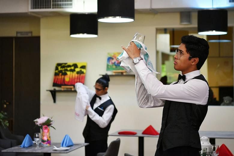 Student Muhammad Nur Haidar Haziq Nordin, 19, cleaning glassware at the school's cafe as part of his ITE skills certification course in hospitality services.
