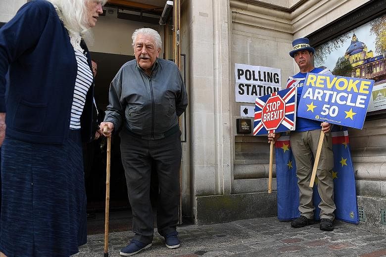 Voters leaving a polling station in London as an activist and Remain EU campaigner makes his stand outside. Britain voted in the European polls on Thursday, and the election continues on the continent this weekend, with results expected to start tric