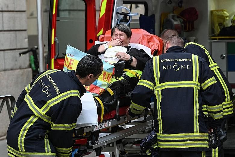 Emergency workers attending to a woman after a suspected package bomb blast in the heart of Lyon, south-east France, on Friday. PHOTO: AGENCE FRANCE-PRESSE