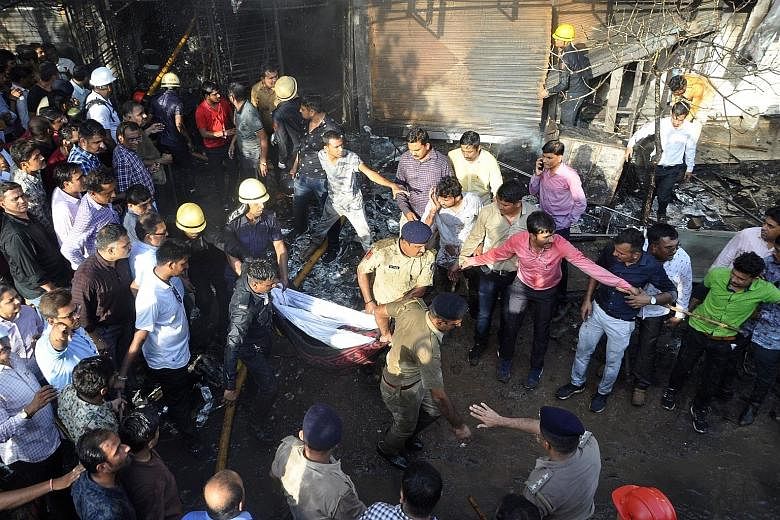 Firefighters and police removing a body from a building housing an illegal tuition centre that caught fire in Surat, in India's Gujarat state, on Friday. Sixteen of the dead were young women who had been preparing for exams at the tuition centre.