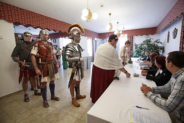 Colonia Rostallo Cultural and Military History Foundation members in ancient Roman legionary costumes at a polling station in Hungary yesterday.