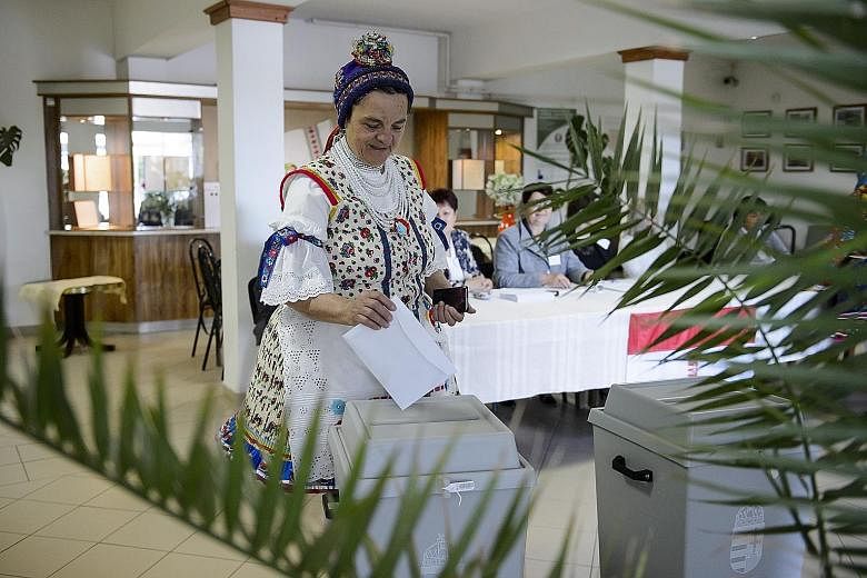 A woman in folk attire casting her ballot at a polling station in Bujak, Hungary, yesterday. The marathon election is expected to further dent traditional pro-European Union parties and bolster the nationalist fringe in the European Parliament. PHOTO