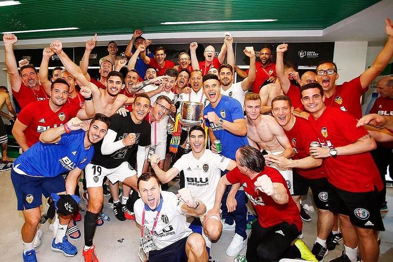 Left: Valencia chairman Anil Murthy (behind the trophy), players and coaching staff celebrating their 2-1 victory over Barcelona in the King's Cup final on Saturday. Below: Kevin Gameiro (No. 9) scoring the opener at the Benito Villamarin stadium in 